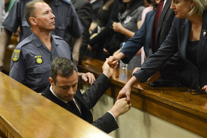 Oscar Pistorius holds the hands of family members as he is taken down to the holding cells after being sentenced to five years imprisonment for the culpable homicide killing of his girlfriend Reeva Steenkamp at the high court in Pretoria, Tuesday, 21 October 2014. Picture: Herman Verwey/Media24/Pool