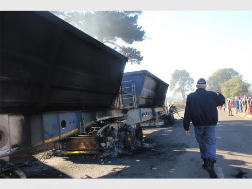 A colonel from the Roodepoort Police walking past the burnt out truck, on his way to speak to a group of angry residents. Photo: Sonwabile Antonie