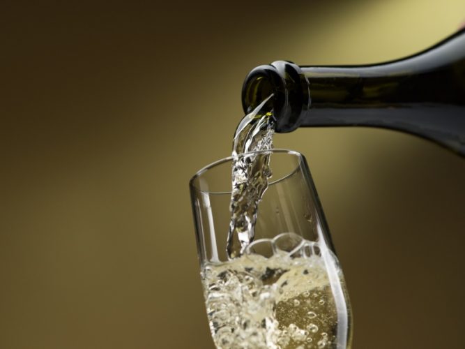 Pouring white wine from a bottle into a wineglass: celebration and wine tasting