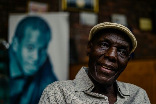Zimbabwe music icon Oliver 'Tuku' Mtukudzi, pictured in January 2018. Over his shoulder is a portrait of his late son, Sam Mtukudzi. AFP/Jekesai NJIKIZANA