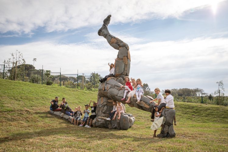 Kids on the oversized upside-down giant by artist Angus Taylor at Norval Foundation in Cape Town
