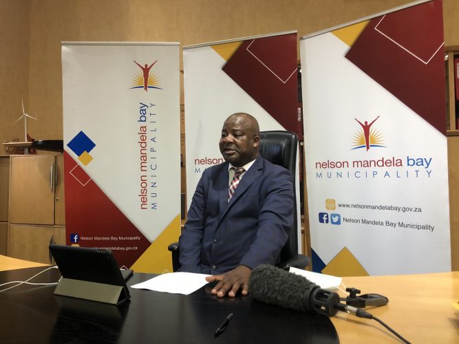 Nqaba Bhanga speaking behind a desk