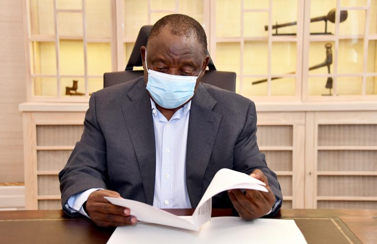 President Cyril Ramaphosa reading a document while wearing a mask.