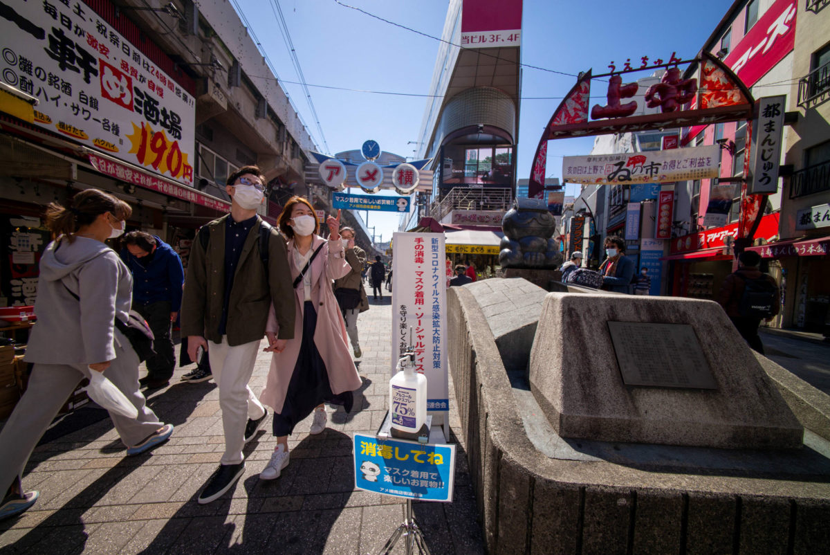 An alcohol bottle (bottom) is installed on a street of Ueno shopping district to encourage shoppers to disinfect their hands in Tokyo on March 14, 2021 to prevent infection with the COVID-19 coronavirus. (Photo by Kazuhiro NOGI / AFP)