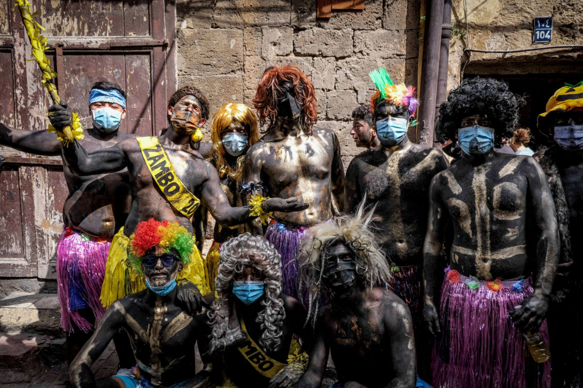 Carnival participants dressed in costume and wearing body paint pose for a group picture during the annual Zambo carnival held in Lebanon's northern city of Tripoli on March 14, 2021, marking the last period of excess on the eve of the Christian Greek Orthodox lent. - The inspiration of the annual Zambo celebration is unclear, despite it being a tradition that stretches back over a century to when an emigrant to Brazil returned to his native Tripoli bringing the carnival with him. (Photo by Ibrahim CHALHOUB / AFP)