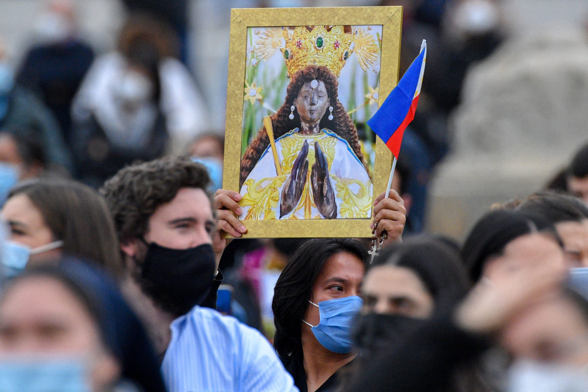 A Philippine attendee holds a picture of Our Lady of the Philippines, and the Philippine flag during the Pope's weekly Angelus prayer on March 14, 2021 at St. Peter's Square in The Vatican. (Photo by Tiziana FABI / AFP)