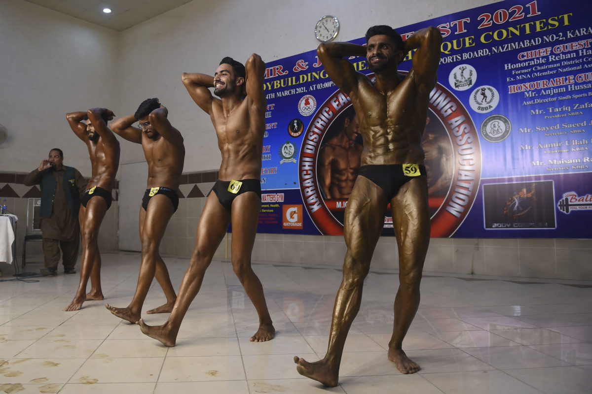 Bodybuilders flex their muscles during a bodybuilding competition in Karachi on March 14, 2021. (Photo by Rizwan TABASSUM / AFP)