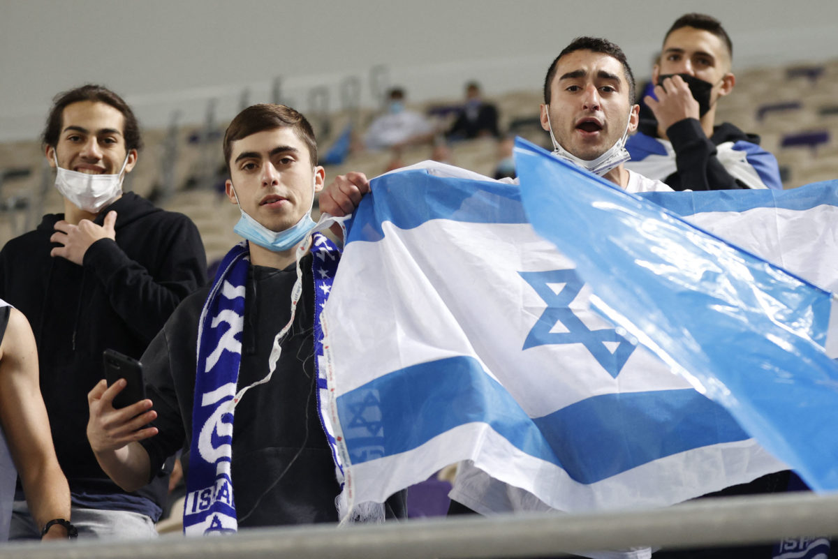 ISraeli fans cheer ahead of the 2022 FIFA World Cup qualifier group F football match between Israel and Denmark at Bloomfield stadium in the Israeli Mediterranean coastal city of Tel Aviv on March 25, 2021. (Photo by JACK GUEZ / AFP)
