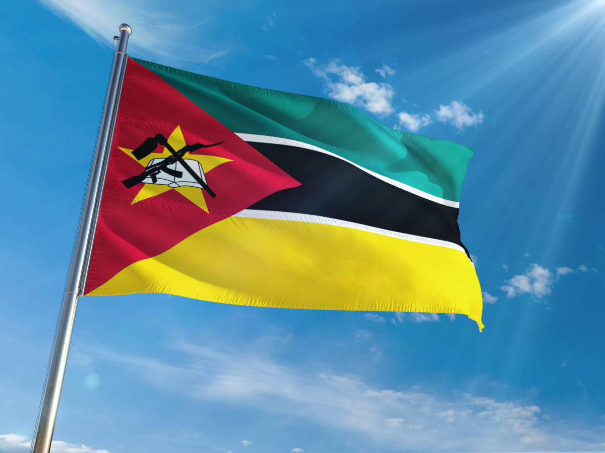 Mozambique National Flag Waving on pole against sunny blue sky background. High Definition