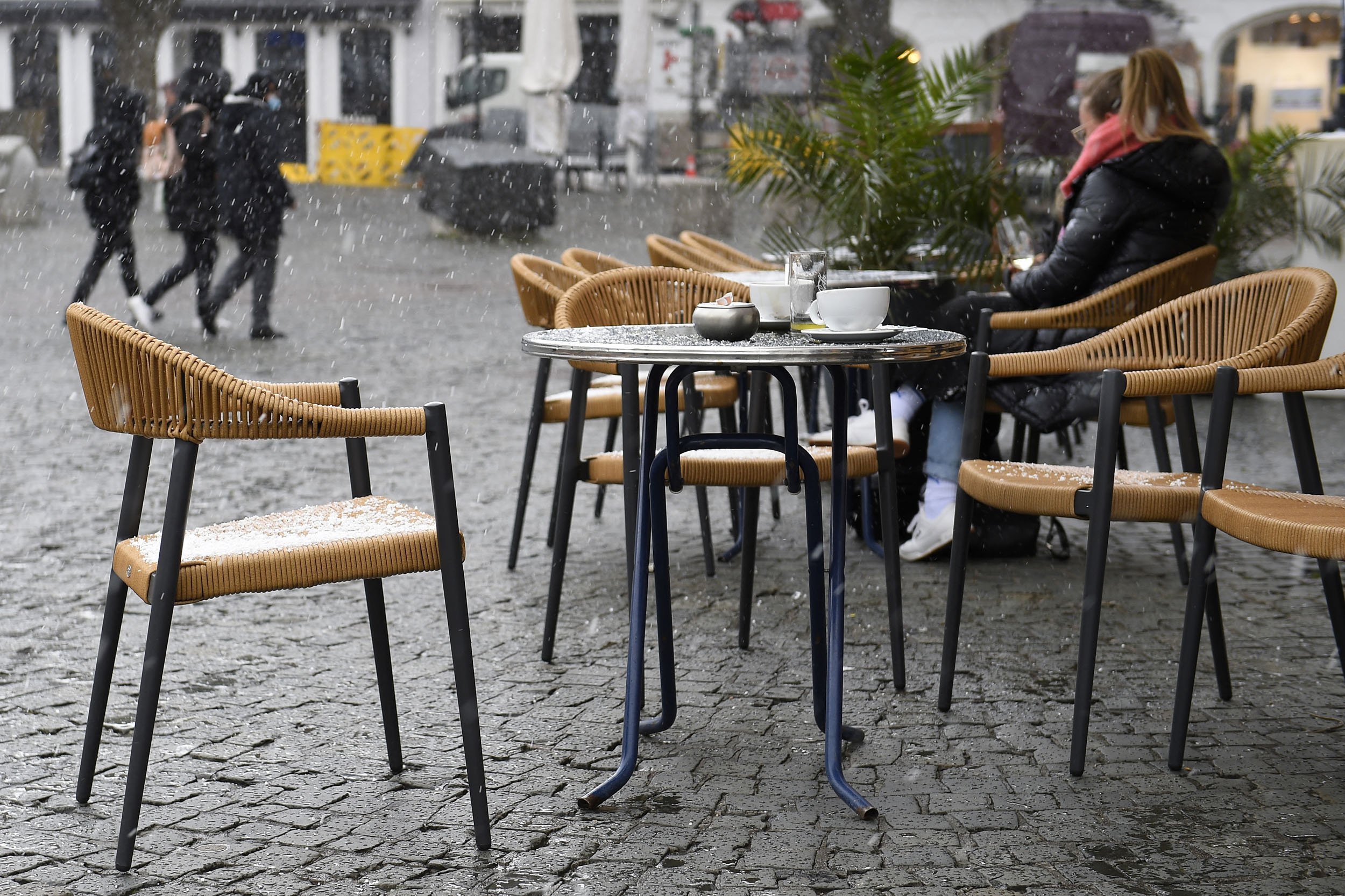An empty table is seen outside a cafe during a sleet shower in Saarbruecken, western Germany, on April 6, 2021, as the border state of Saarland on Tuesday partially reopened during the ongoing coronavirus (Covid-19) pandemic. - Germans in the tiny border state of Saarland returned to cafes, cinemas and cultural venues on April 6, even as the rest of the country faces tighter coronavirus restrictions amid rising case numbers. (Photo by JEAN-CHRISTOPHE VERHAEGEN / AFP)