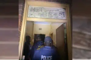 Police entering a hijacked building with a sign that says not welcome.