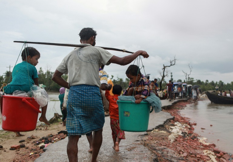 A Rohingya refugee carries two children in buckets as they arrive in Bangladesh at Shah Porir Dwip in Teknaf